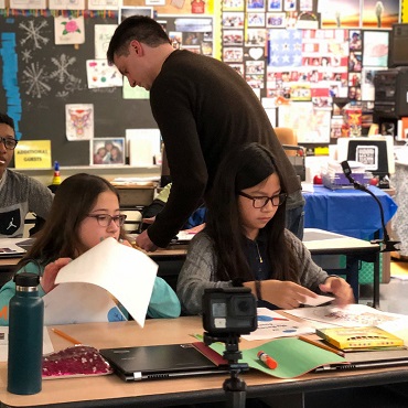 A researcher helps two children during a workshop about creative artificial intelligence.