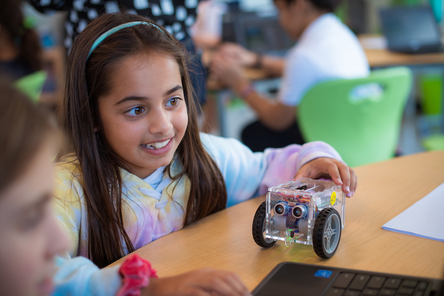 Kids program their robot using Scratch blocks on a laptop.